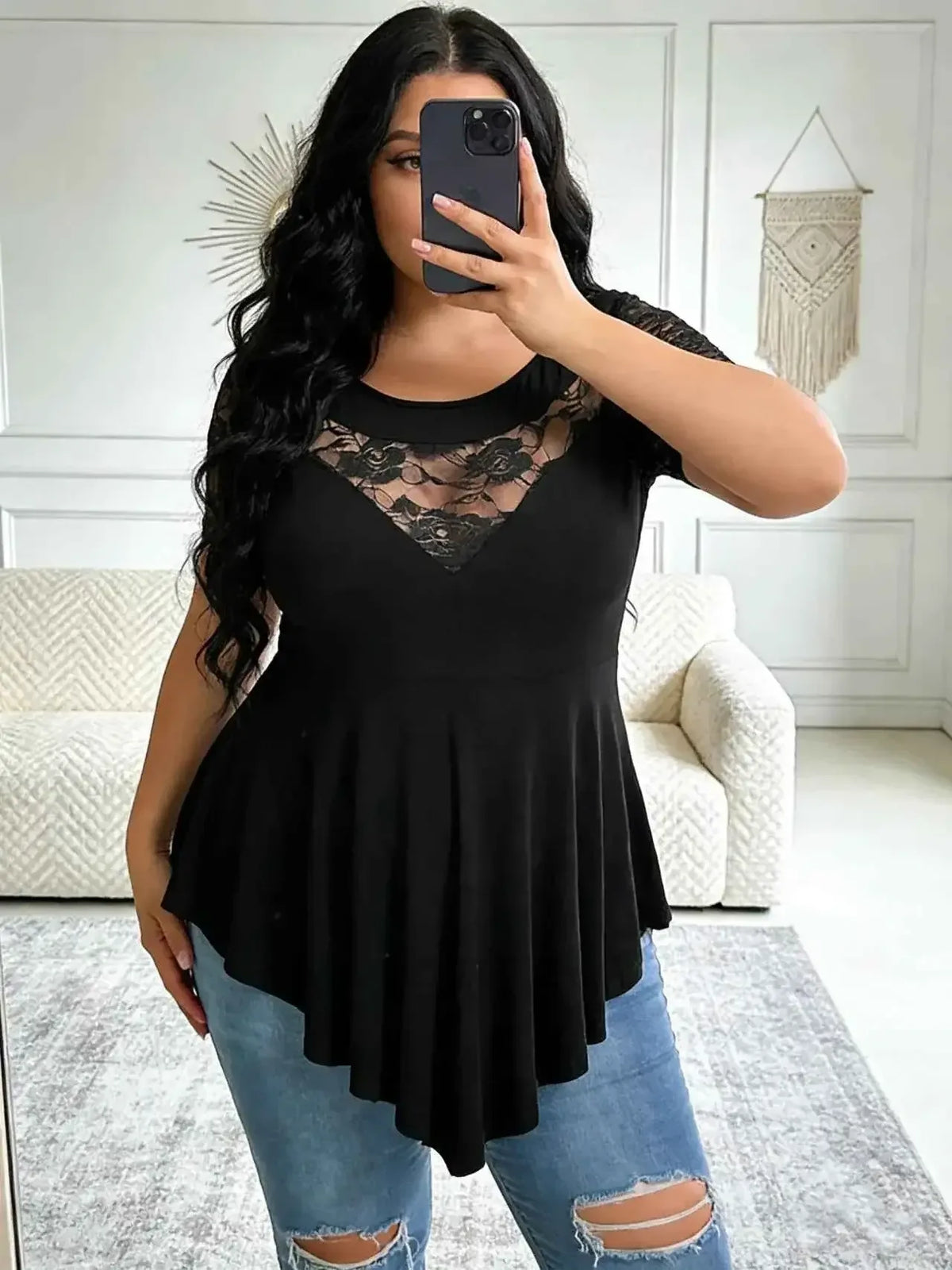 Top tunica pizzo taglie forti, camicetta nera fluida con orlo asimmetrico e maniche corte indossata da una donna curvy.