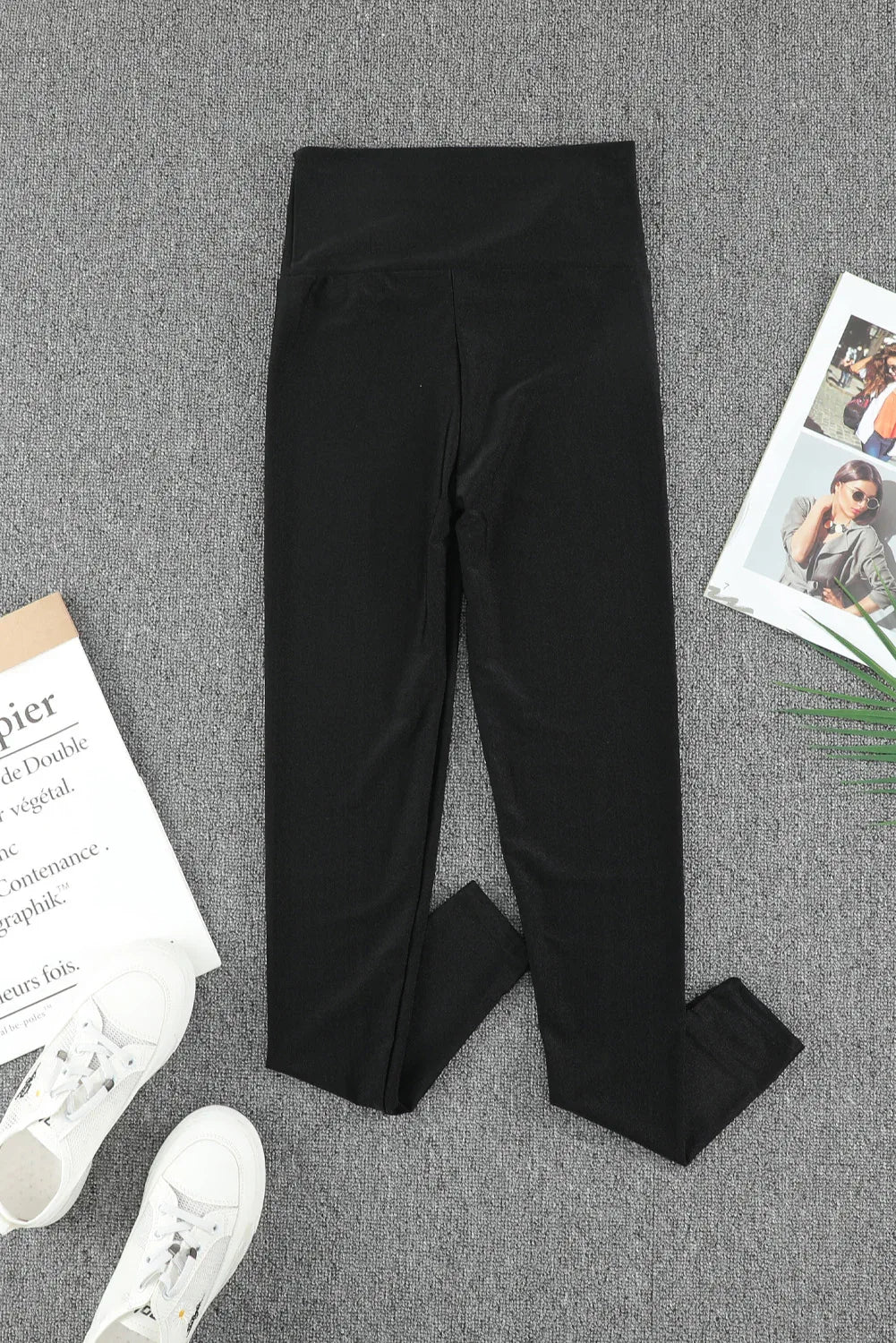Leggings modellanti vita alta push-up neri su sfondo grigio con scarpe bianche e riviste decorative.